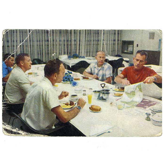 Apollo 11:n lähtöpäivän aamuna 16. heinäkuuta 1969 astronautit Neil  Armstrong, Edwin Aldrin ja Michael Collins söivät tukevan aamiaisen. Miehistöpäällikkö Donald Slayton esitteli sääennusteita. (numero 27)